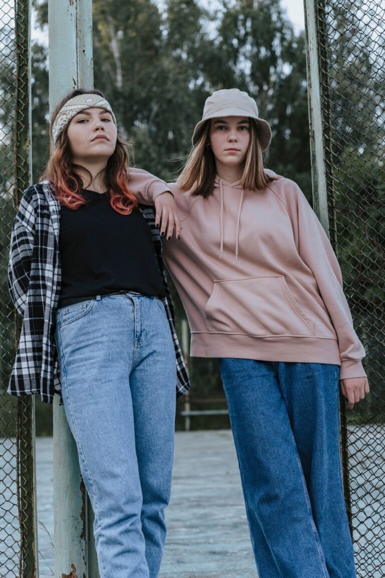 Dwie nastolatki w jeansach, koszuli w kratę i bluzie z kapturem