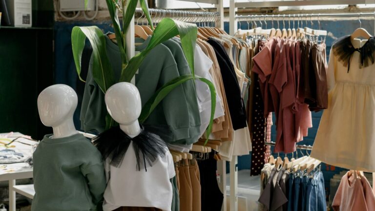Bluzy i koszulki w odcieniach zieleni i beżu na wieszakach w sklepie z odzieżą dziecięcą