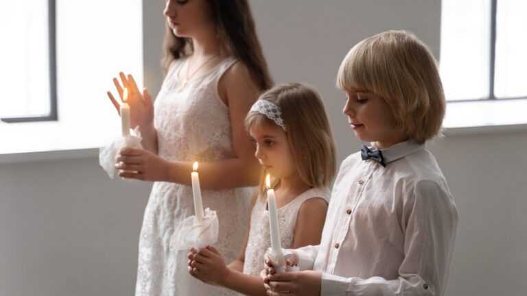 Dzieci w białych strojach i koszuli z muszką trzymają świece podczas występu